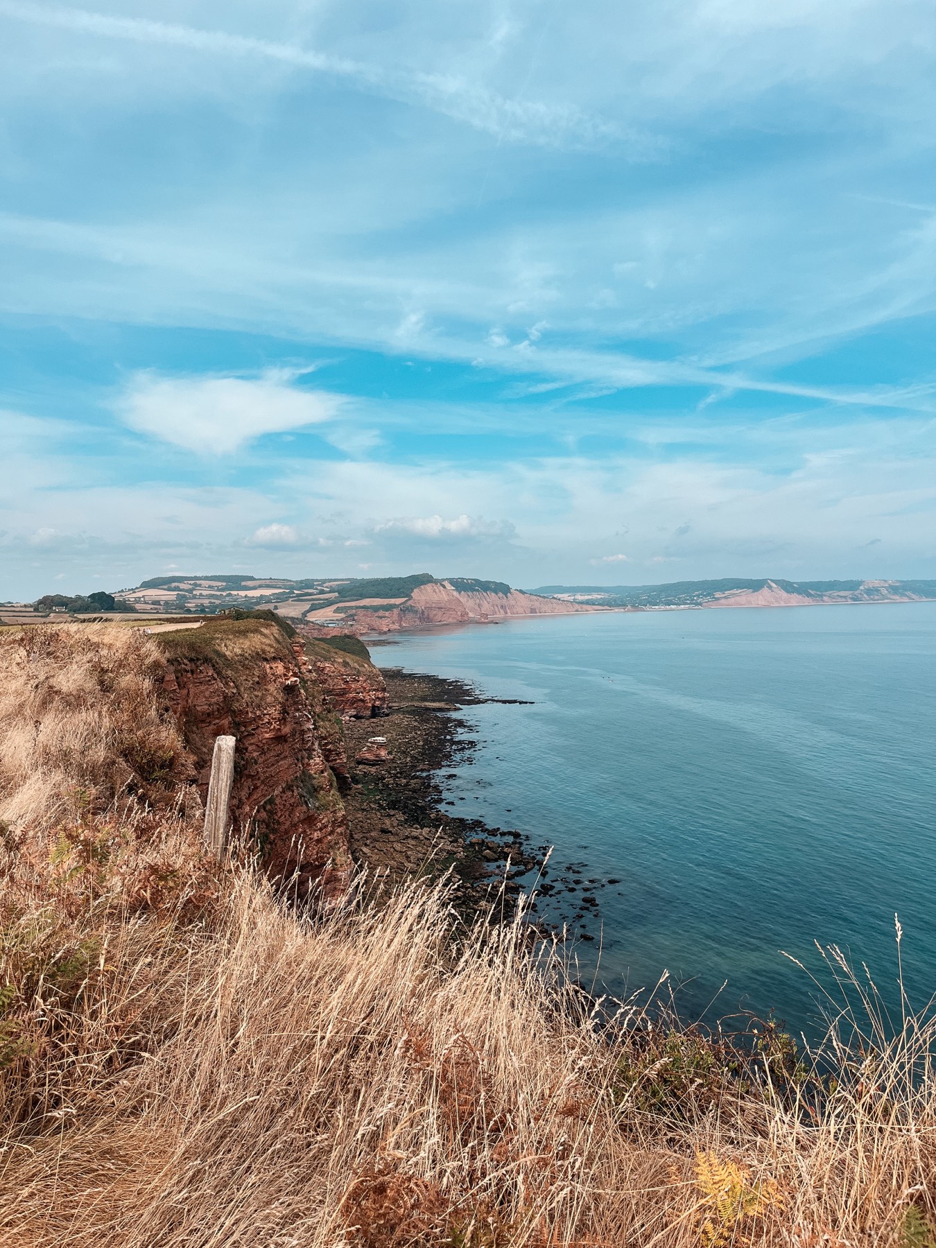 Red Jurassic Coast cliffs curving toward Sidmouth Bay