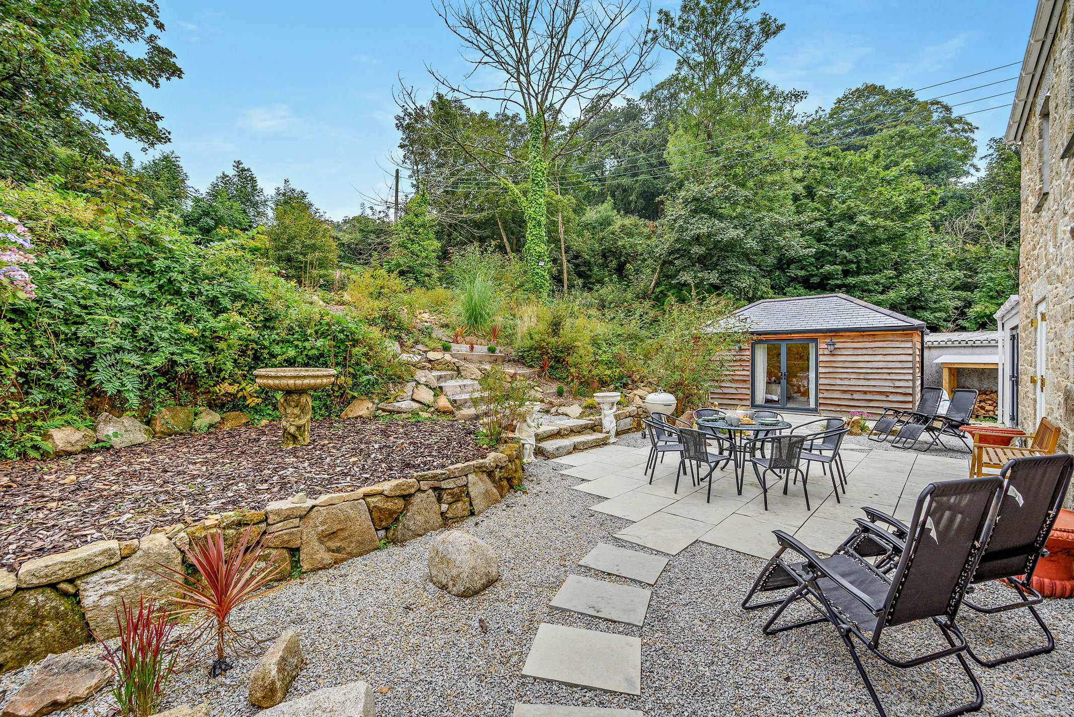 The garden at The Falmouth Garden House with stream and tropical plants